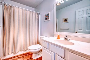 A bathroom with a striped shower curtain, a white toilet, a sink with an orange soap dispenser, and a mirror reflecting a door. - Waterfront/Private Pier, Water Access/Pool&Tennis club/Kayaks/SUP/ping-pong (Avon)