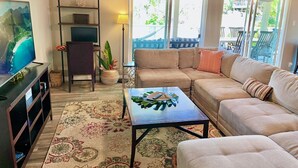 A living room with a TV, sofa, coffee table, and a decorative plant. - Modern 3 Bedroom Family Friendly Kihei Home Near Beach (Kihei)
