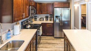 A modern kitchen with wooden cabinets, stainless steel appliances, a double sink, and a large island. - Modern 3 Bedroom Family Friendly Kihei Home Near Beach (Kihei)