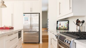 Cocina moderna con armarios blancos, un refrigerador de acero inoxidable, una estufa a gas y un microondas.