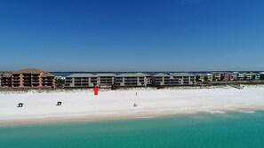 Een hotel aan het strand met meerdere gebouwen, een zandstrand en helder turquoise water.
