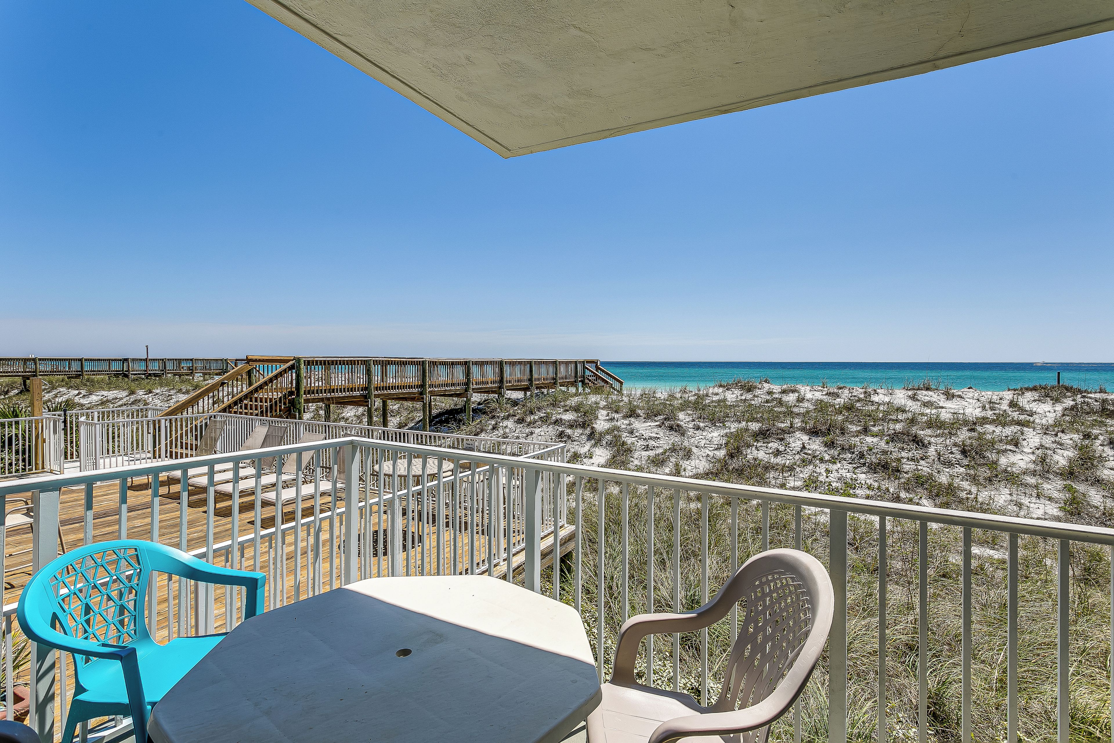 Ein Balkon mit Blick auf den Strand, einer Holzterrasse und zwei Stühlen.