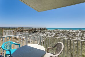 Un balcon avec vue sur la plage, une terrasse en bois et deux chaises.
