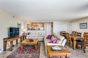 Ein Wohnzimmer mit einer Couch, einem Couchtisch, einem Fernseher und einem Essbereich mit Stühlen und einem Tisch.