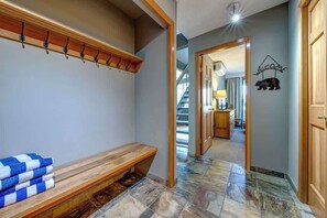 A hallway with a bench, a coat rack, and a welcome sign. - Greystone Lodge 311 Ski-in/Out by Acer Vacations (Whistler)