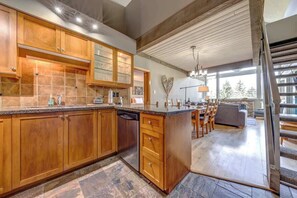 A spacious kitchen with wooden cabinets, a dishwasher, and a large island. - Greystone Lodge 311 Ski-in/Out by Acer Vacations (Whistler)