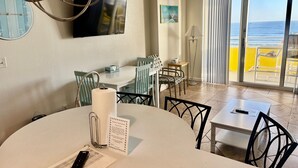A hotel room with a dining area, a TV, a view of the beach, and a balcony with yellow railings. - Ocean Walk Resort  505 Ocean Front (Daytona Beach)