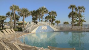 A pool area with lounge chairs, palm trees, and a staircase leading to a deck. - Ocean Walk Resort  505 Ocean Front (Daytona Beach)