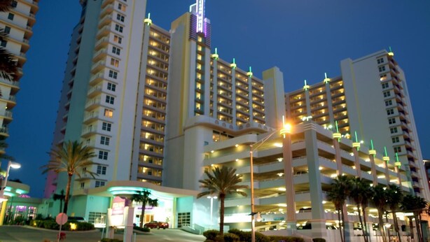 A multi-story hotel with a prominent neon sign, multiple parking levels, and a well-lit entrance area. - Ocean Walk Resort  505 Ocean Front (Daytona Beach)