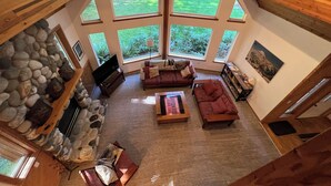 Un salón amplio con chimenea de piedra, ventanas grandes y una zona de estar acogedora.