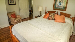 Ein Schlafzimmer mit einem großen Bett, einem Sessel, einem Nachttisch und einer Tür.