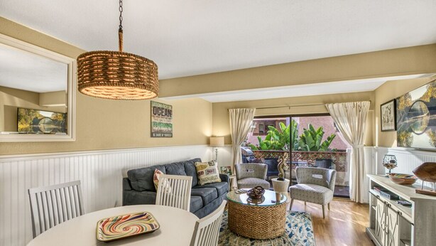 A cozy living room with a sofa, chairs, a dining table, and a hanging light fixture.