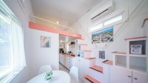 A modern kitchen with white cabinets, a dining area with a white table, and a view of the city through a window.