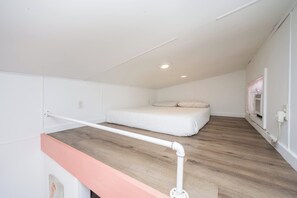 Ein Schlafzimmer mit einem Bett, Holzboden, weißen Wänden und einer weißen Decke.