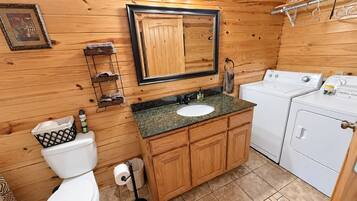 A compact bathroom with a wooden vanity, a sink, a toilet, and a washing machine.