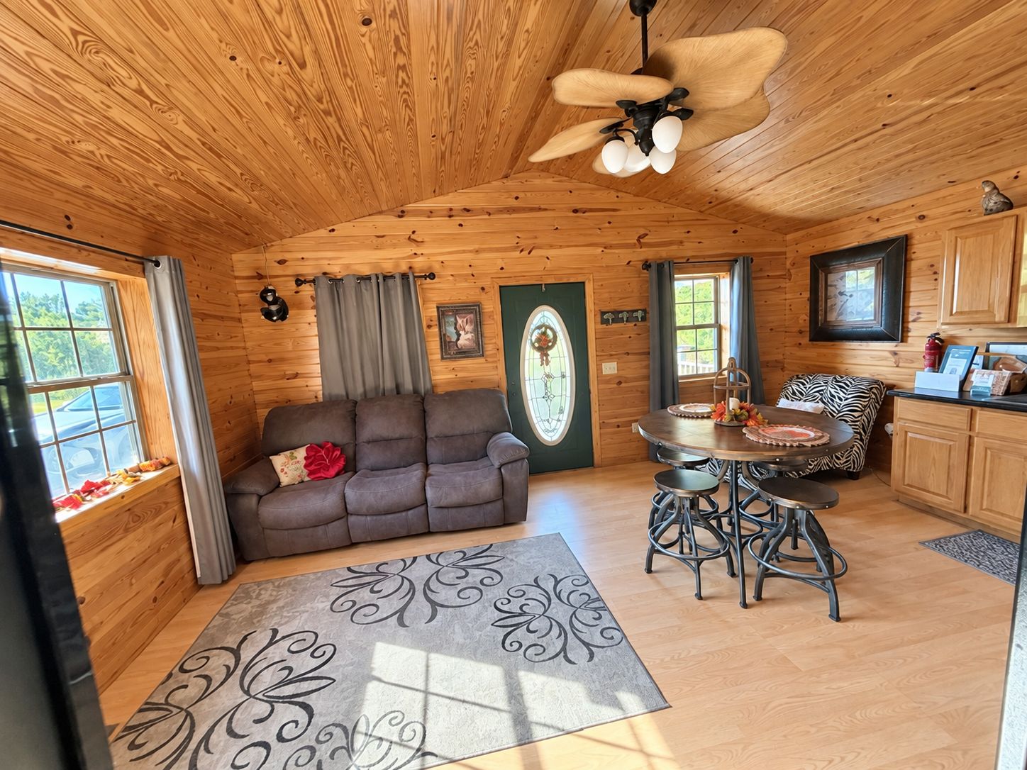 Un interior de cabaña acogedor con sofá, mesa de comedor y zona de cocina.