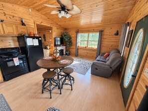 A cozy cabin interior with a kitchen, dining area, and seating space. - Secluded cabin on 450 acres. Hot tub, and private UTV trails. Pet friendly! (Hatfield)