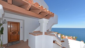 A white building with a wooden door and a view of the sea. - H319: 1BD Villa w/ Spectacular Views,Fireplace,Romantic Private Balcony,NEW Cart (Avalon)
