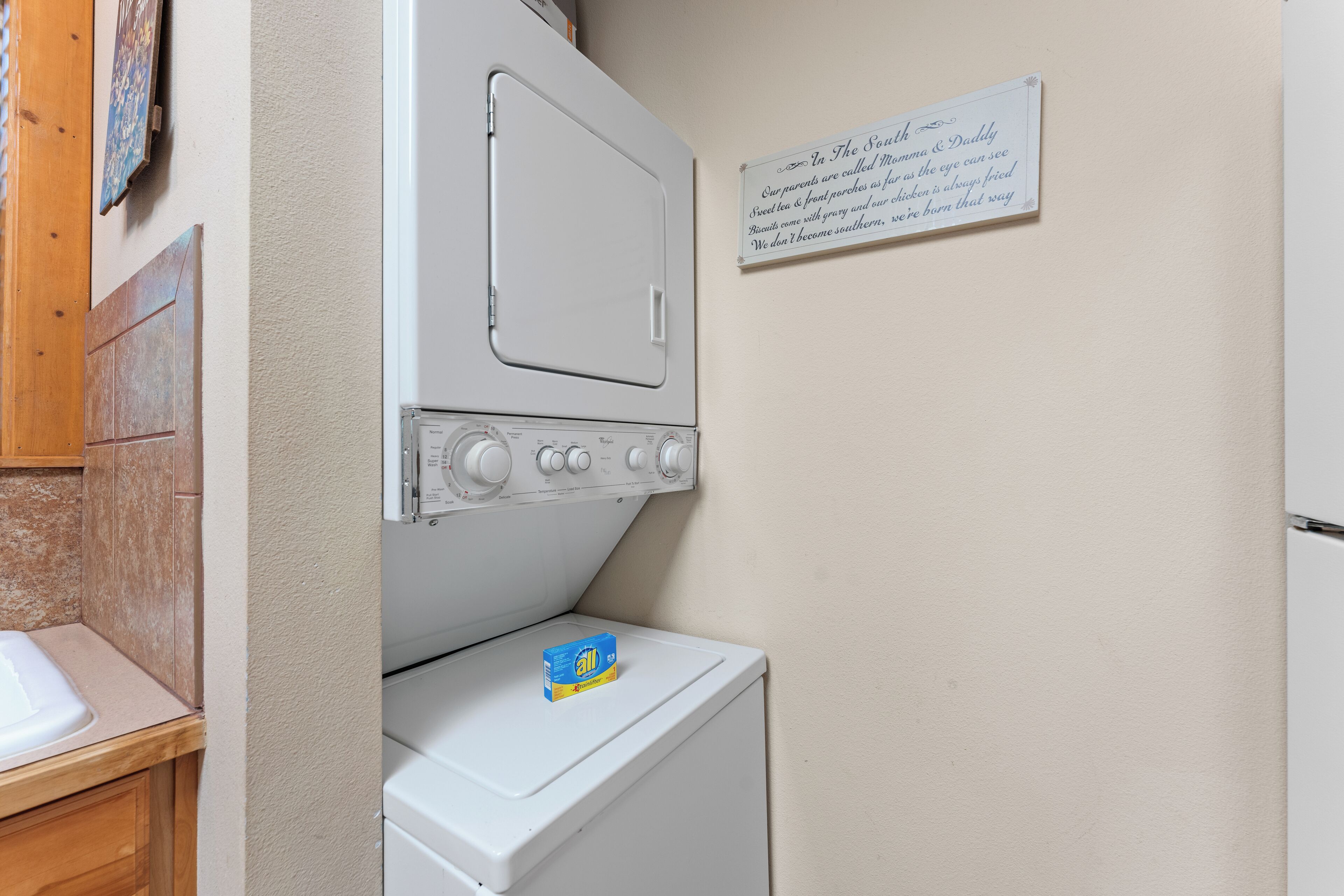 A laundry area with a white washing machine, a dryer, and a wall-mounted sign.