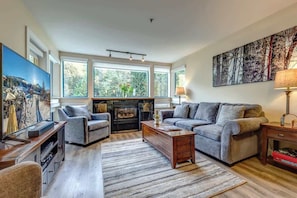 A living room with a fireplace, sofas, a coffee table, and a large painting.