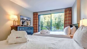 Een hotelkamer met twee bedden, een televisie, een bureau en een raam met gordijnen.