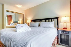 A hotel room with a large bed, bedside lamps, a mirror, and a small table. - Greystone Lodge 226 Ski-in/Out by Acer Vacations (Whistler)
