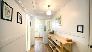 A narrow hallway with a wooden bench, framed pictures on the walls, and a ceiling light fixture. - 334S: Quaint Catalina Cottage, Large Porch, BBQ, WIFI, Min Away from Beach - 334 (Avalon)