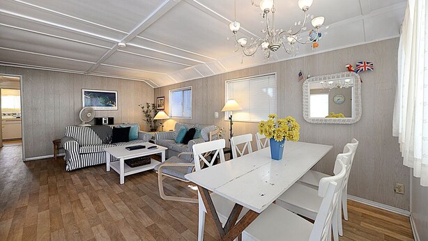 A spacious living area with a white dining table, striped sofa, and a chandelier. - 334S: Quaint Catalina Cottage, Large Porch, BBQ, WIFI, Min Away from Beach - 334 (Avalon)