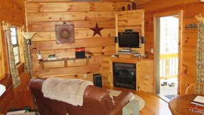 Un intérieur de chalet chaleureux avec une cheminée, un téléviseur et un canapé en cuir.