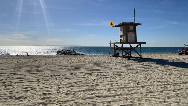 Una torre de salvavidas en una playa arenosa con cielos despejados.