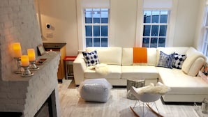 Ein modernes Wohnzimmer mit Kamin, weißen Sofas und Holzboden.