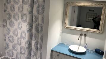 A bathroom with a blue countertop, a white sink, and a mirror with a rope frame.