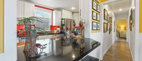 Una cocina moderna con una isla central, armarios blancos y una pared de acento amarilla.