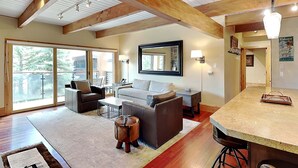 A spacious living area with a large window, a sofa, a coffee table, and a wooden ceiling. - 🌲Timberline D2D Deluxe 2-Bedroom ~Hot Tub~Pool~WiFi~Ski-in/out~Local Shuttle🌲 (Snowmass Village)