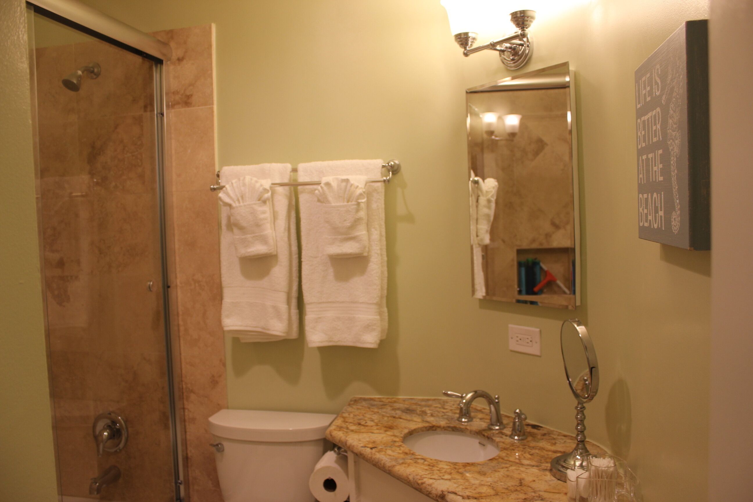 A bathroom with a shower, toilet, sink, and two towels hanging on the wall.
