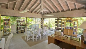 A spacious reading room with high ceilings, large windows, and multiple bookshelves filled with books. - Carolina to Keys Ocean view dream Monthly pricing Best pool on the Island (Key West)