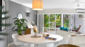 Un comedor moderno con una mesa redonda, sillas blancas y vistas a exuberante follaje exterior.