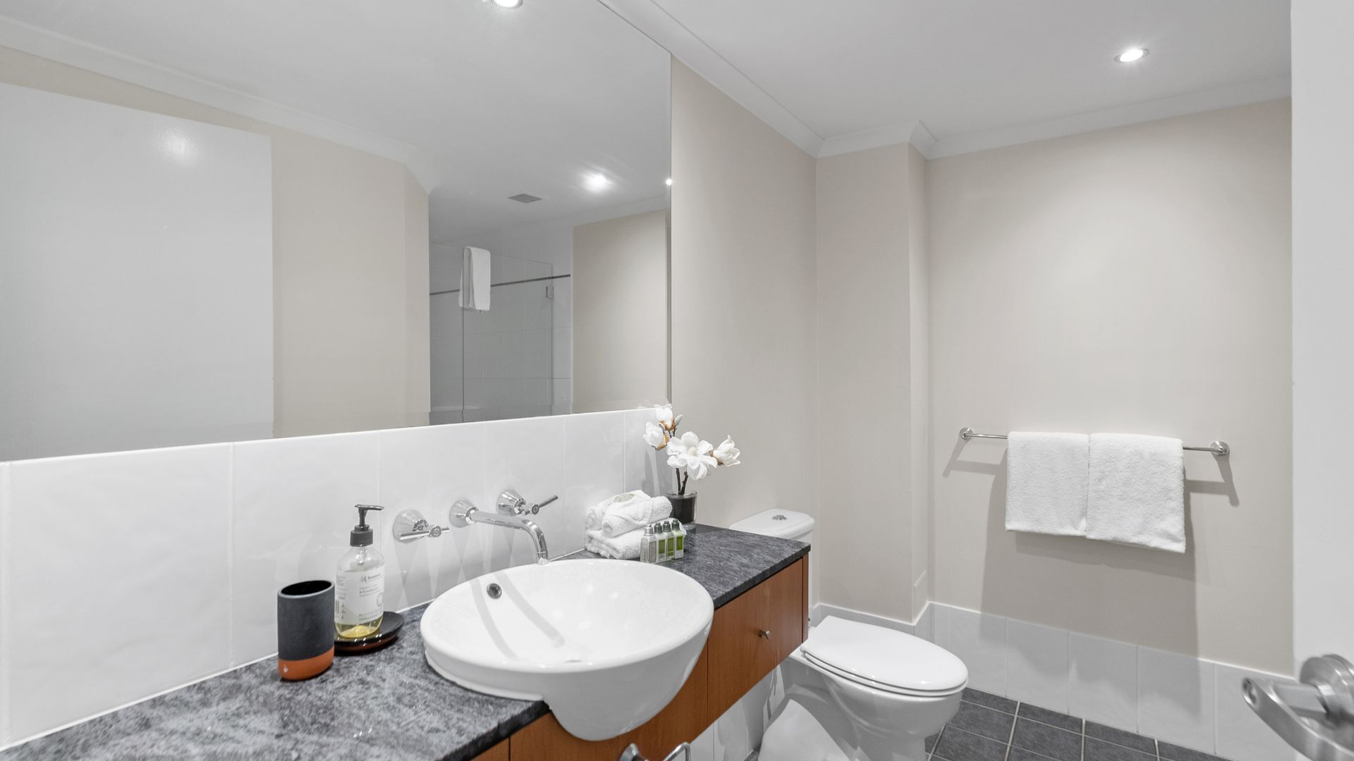 Ein modernes Badezimmer mit Waschbecken, Waschtisch und Toilette, alles in Weiß.