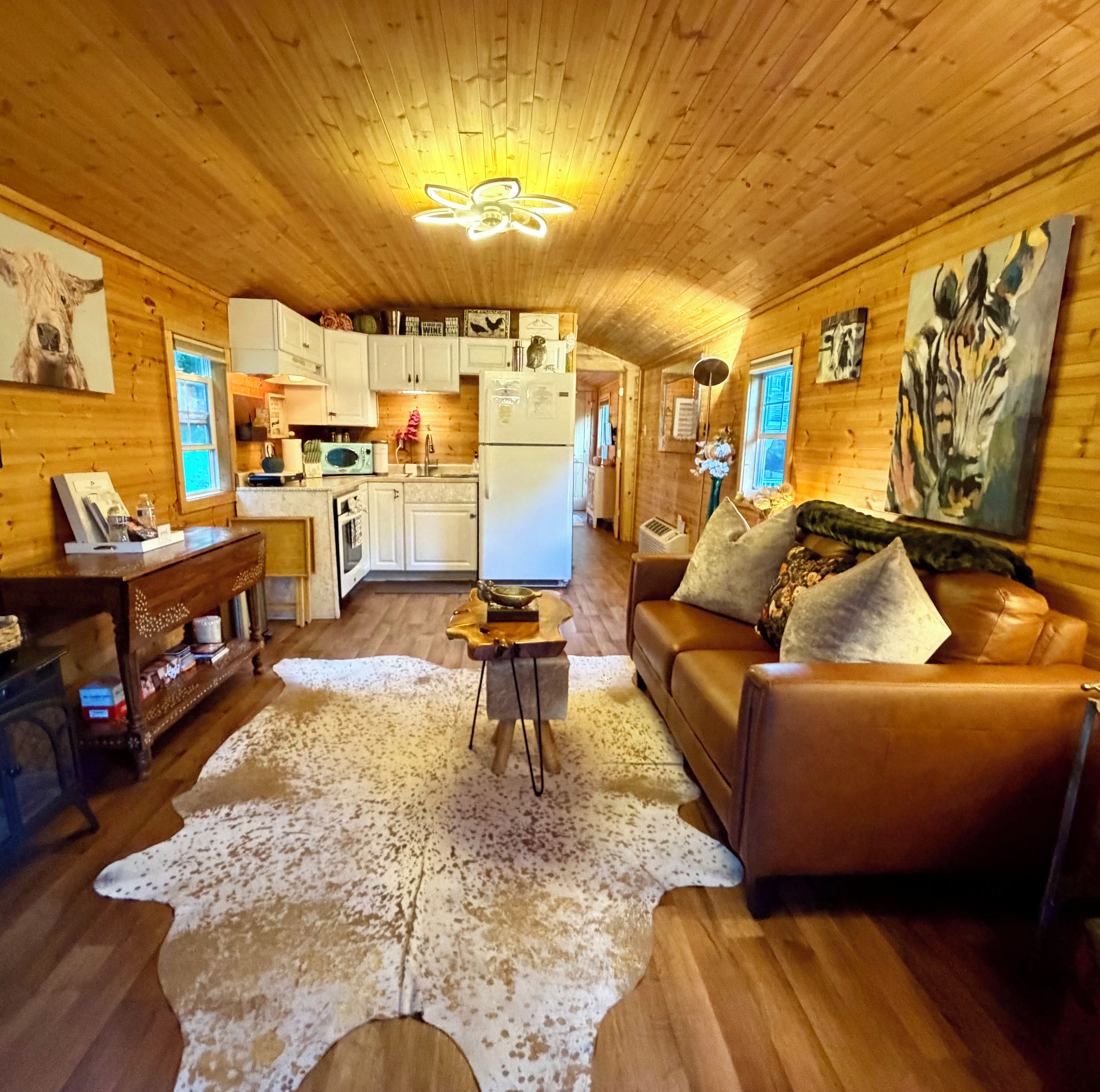 A cozy cabin interior with a living room, kitchen, and a dining area.