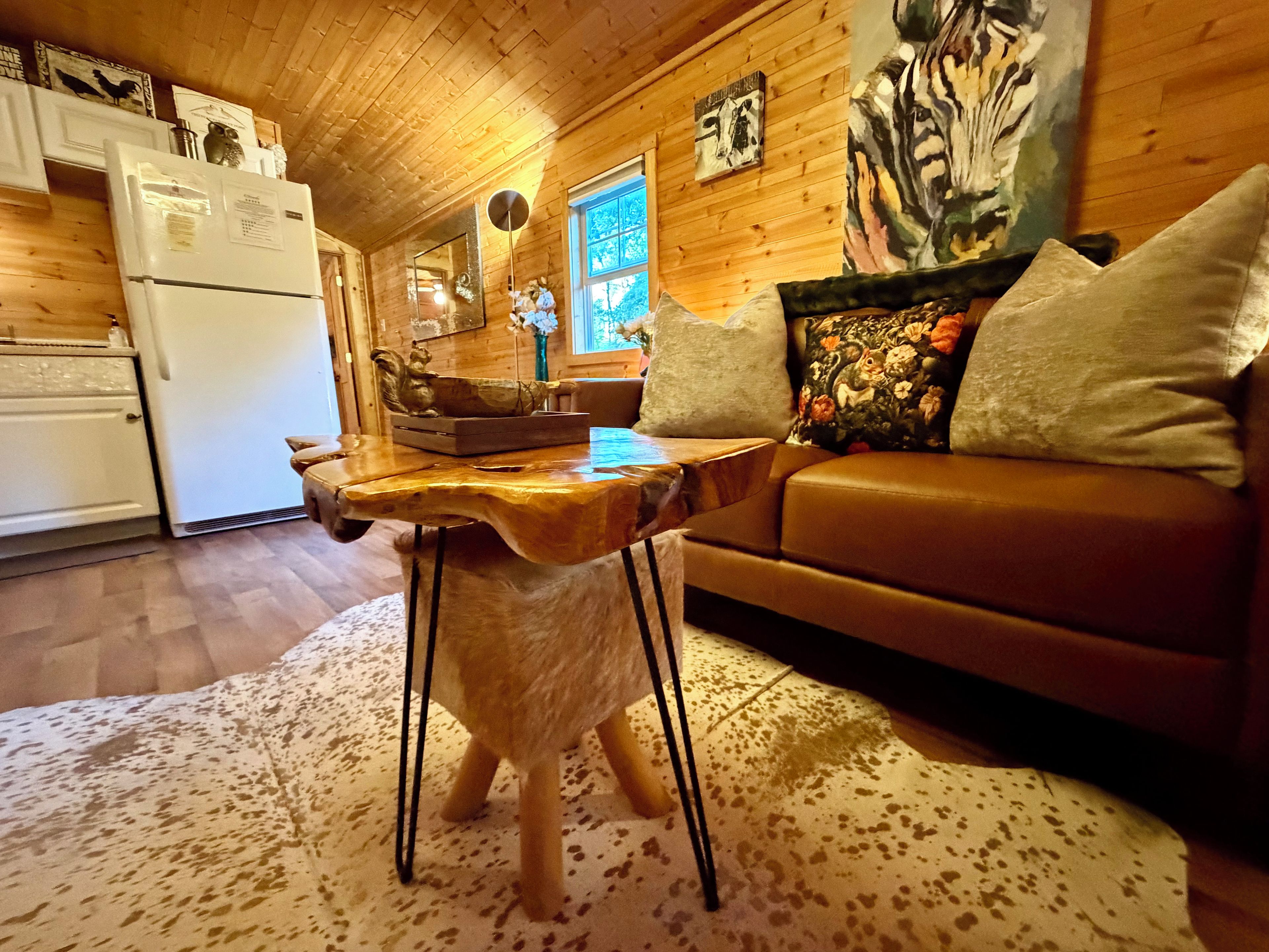A wooden interior with a sofa, a table with a unique design, and a refrigerator.
