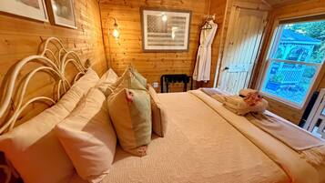 A wooden room with a bed, a framed picture, a light fixture, and a window.