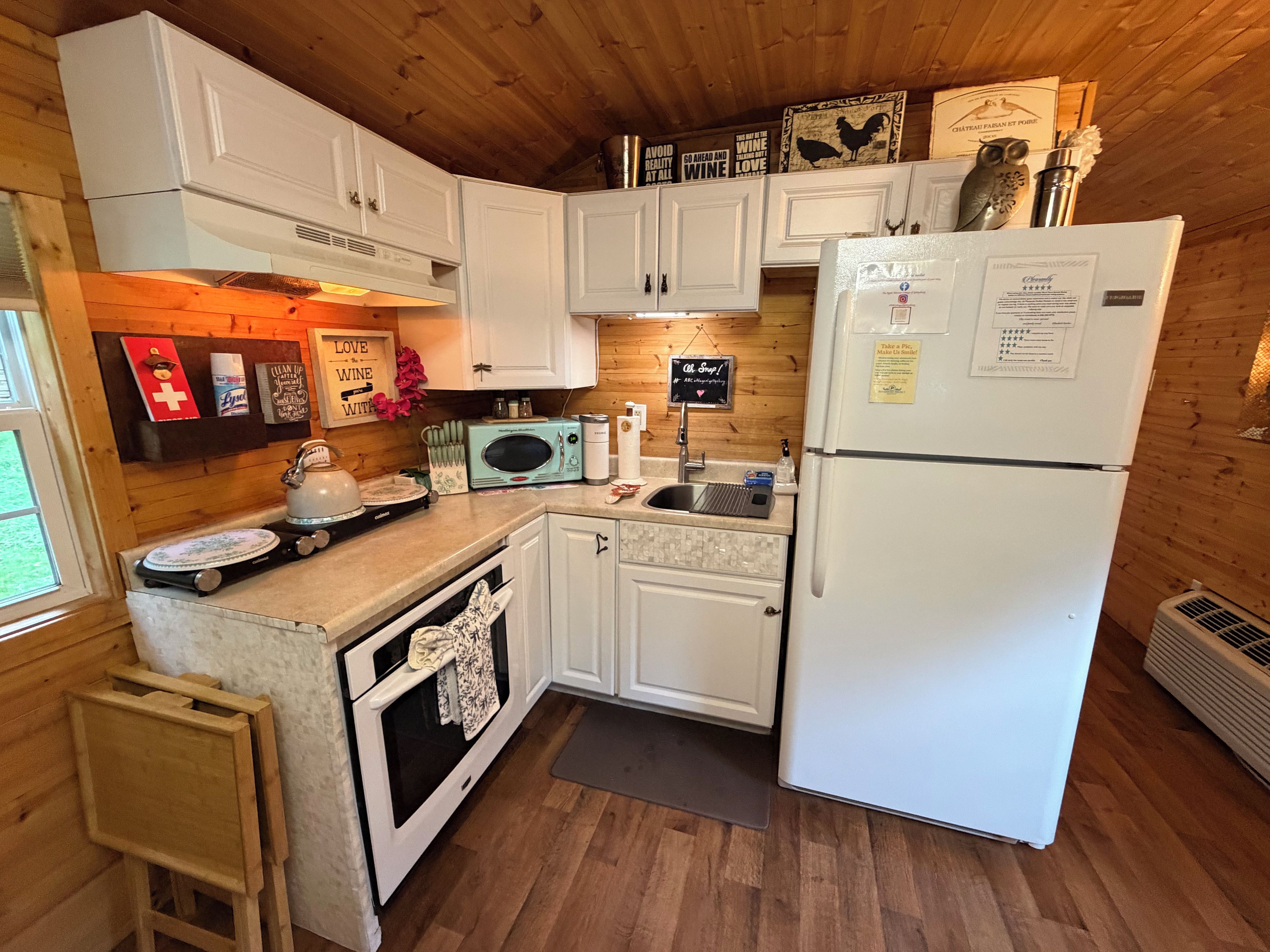 A compact kitchen with white cabinets, a white refrigerator, a microwave, and a sink.