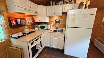A compact kitchen with white cabinets, a white refrigerator, a microwave, and a sink.
