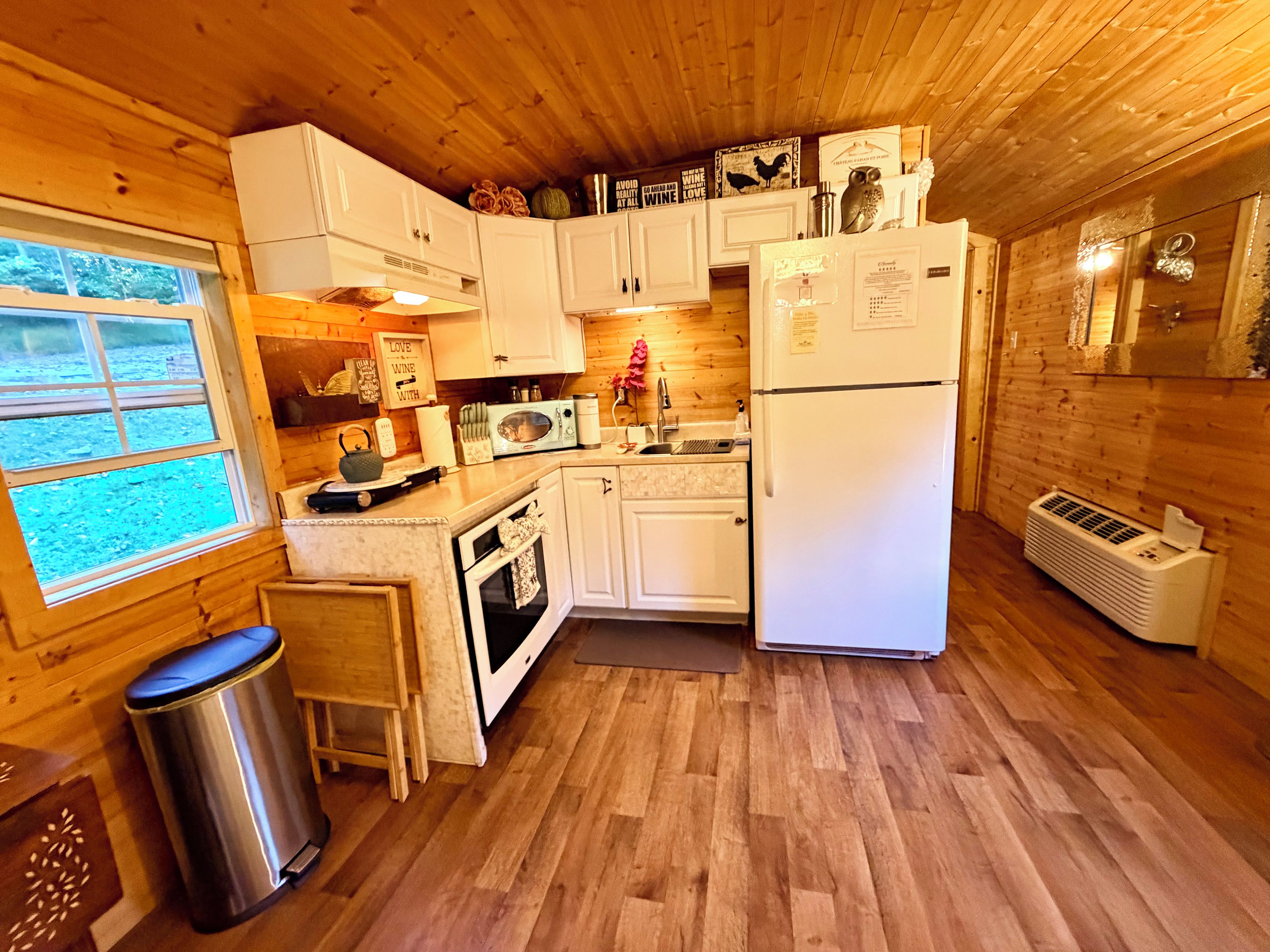 A compact kitchen with white cabinets, a microwave, a sink, and a refrigerator.