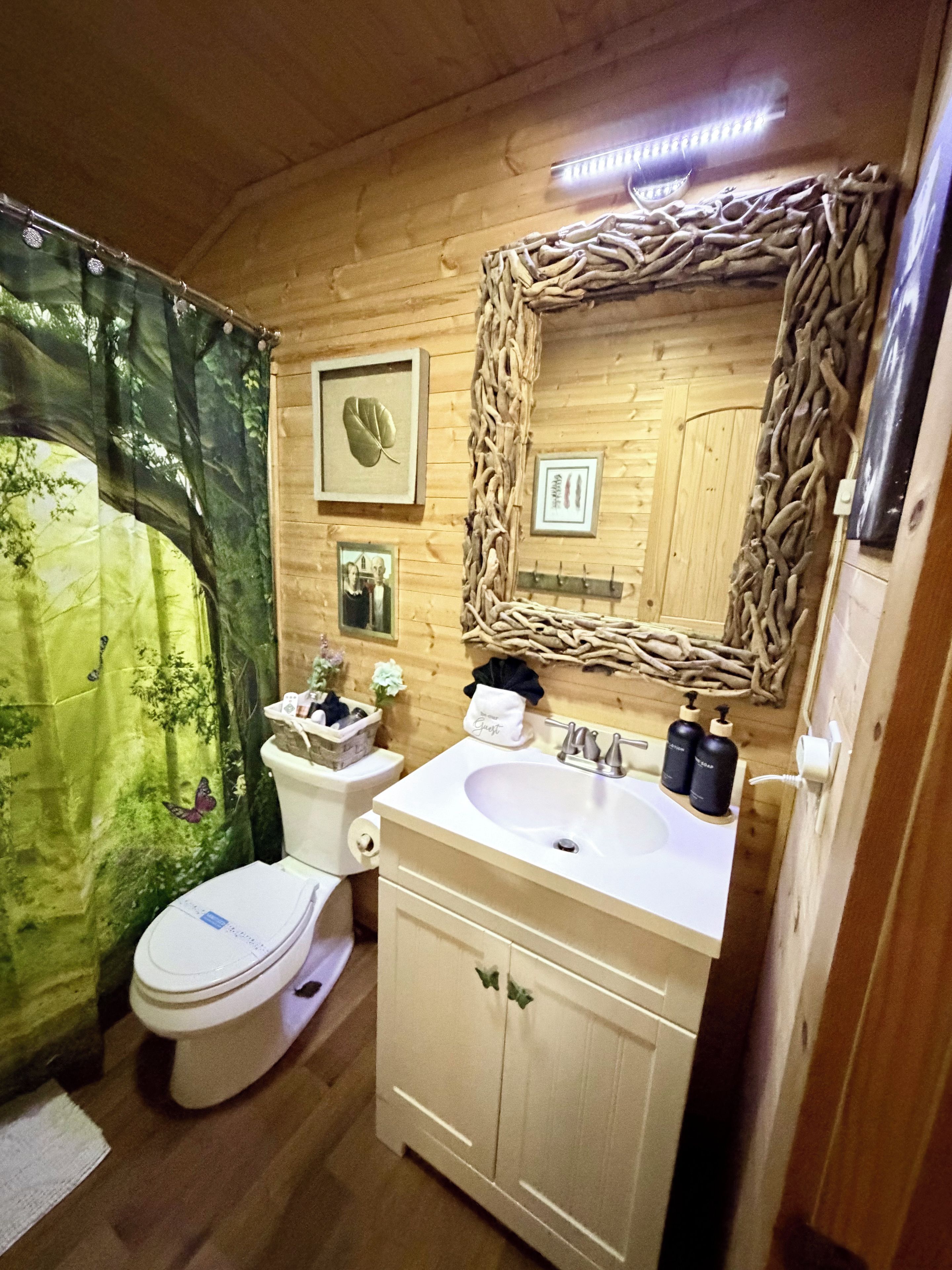 Une salle de bain aux murs lambrissés, équipée de toilettes, d’un lavabo et d’un miroir.