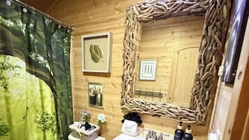 Une salle de bain aux murs lambrissés, équipée de toilettes, d’un lavabo et d’un miroir.