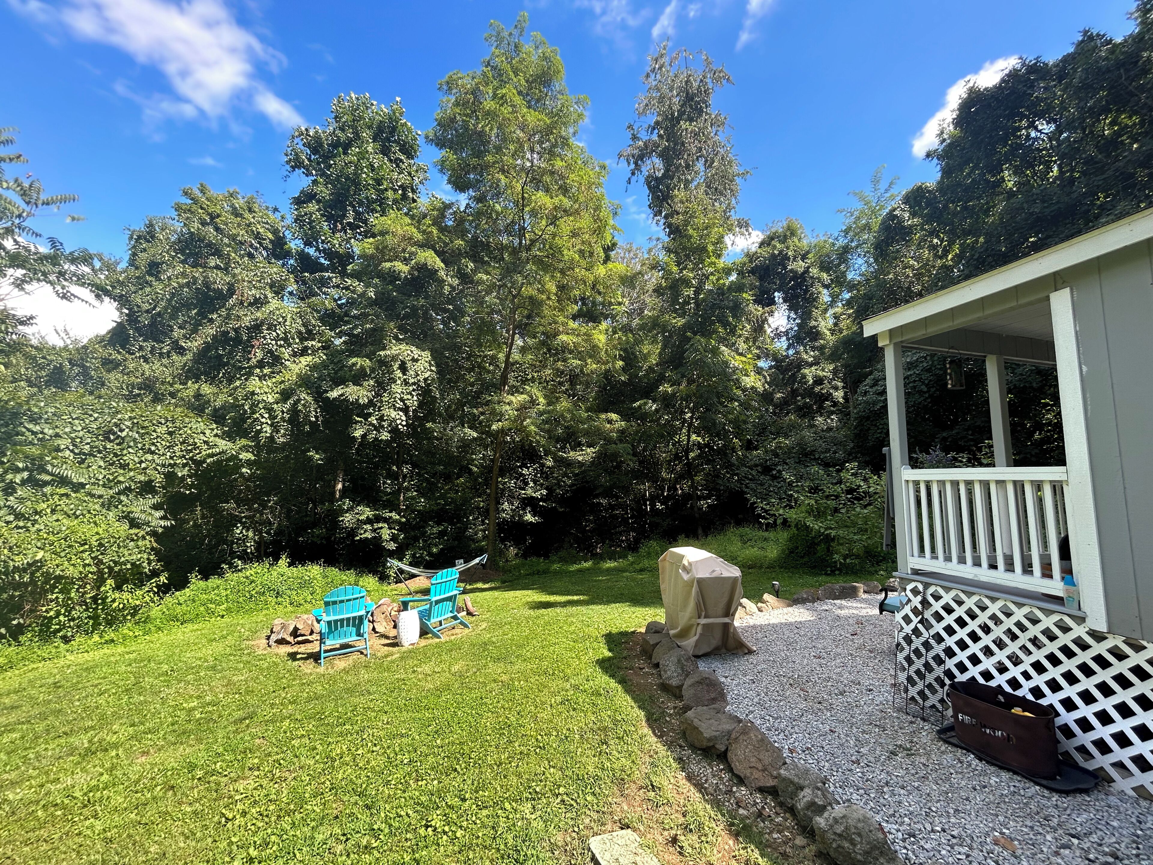 A backyard with a lawn, a covered barbecue area, and a small deck.