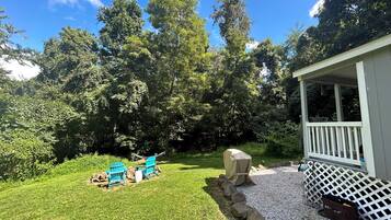 A backyard with a lawn, a covered barbecue area, and a small deck.