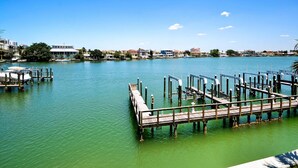 Ein Yachthafen mit Holzstegen und Booten, umgeben von Gebäuden und Bäumen unter blauem Himmel.