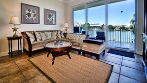 Ein Wohnzimmer mit einer Couch, einem Couchtisch und Blick auf ein Gewässer durch große Fenster.